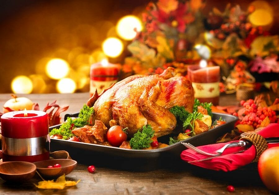 Roasted Turkey. Thanksgiving table served with turkey, decorated with bright autumn leaves and candles. Roasted chicken, table setting. Christmas dinner